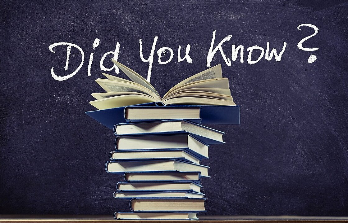 Tafel mit Bücherstapel davor. Auf der Tafel steht: Did you know?