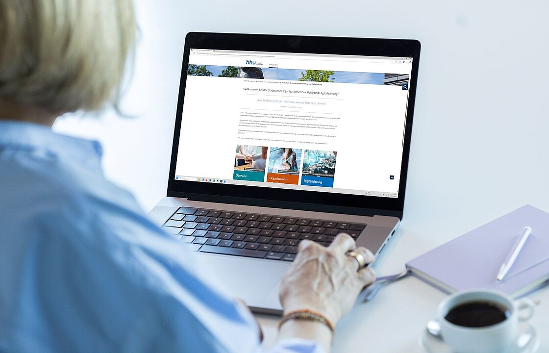 Eine Person vor einem Laptop, auf dem die neuen Seiten der Stabsstelle OED zu sehen sind.