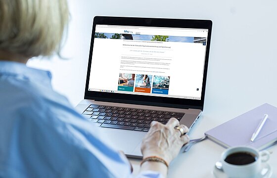 Eine Person vor einem Laptop, auf dem die neuen Seiten der Stabsstelle OED zu sehen sind.