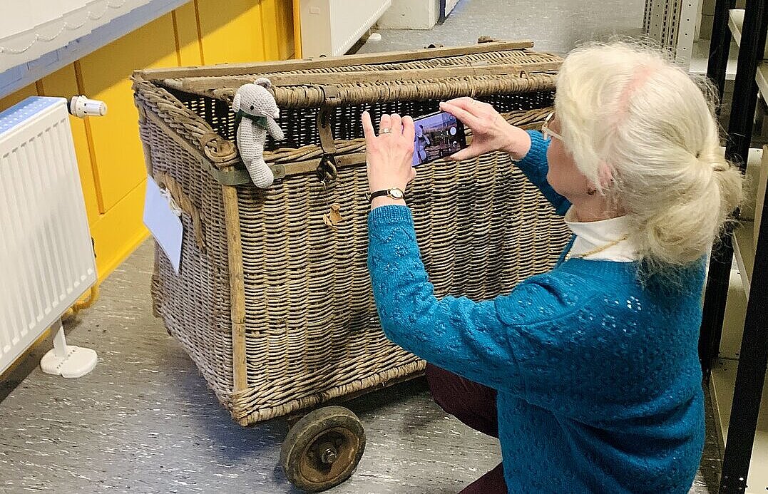 Maria Wego fotografier mit dem Handy eine kleine Stoffmaus in einem fahrbaren Korb.