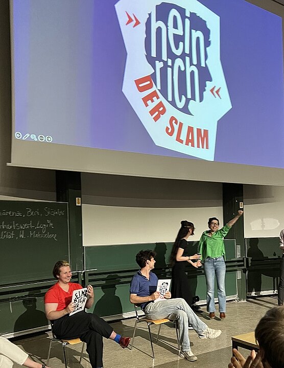 Die Gewinnerin des HEINRICH Sara Ipakchi auf der Bühne und weitere Teilnehmende des Abends