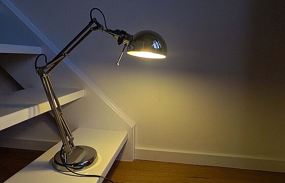 Eine silberfarbene Lampe steht auf einer weißen Treppenstufe