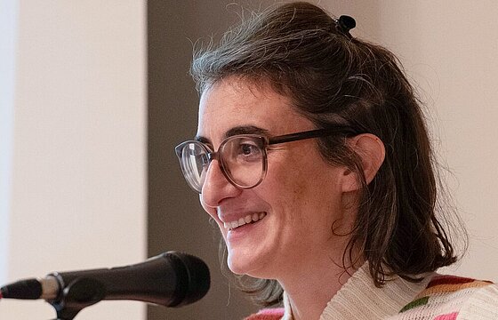 Seitliche Aufnahme von Christine Bratu am Mikrofon.