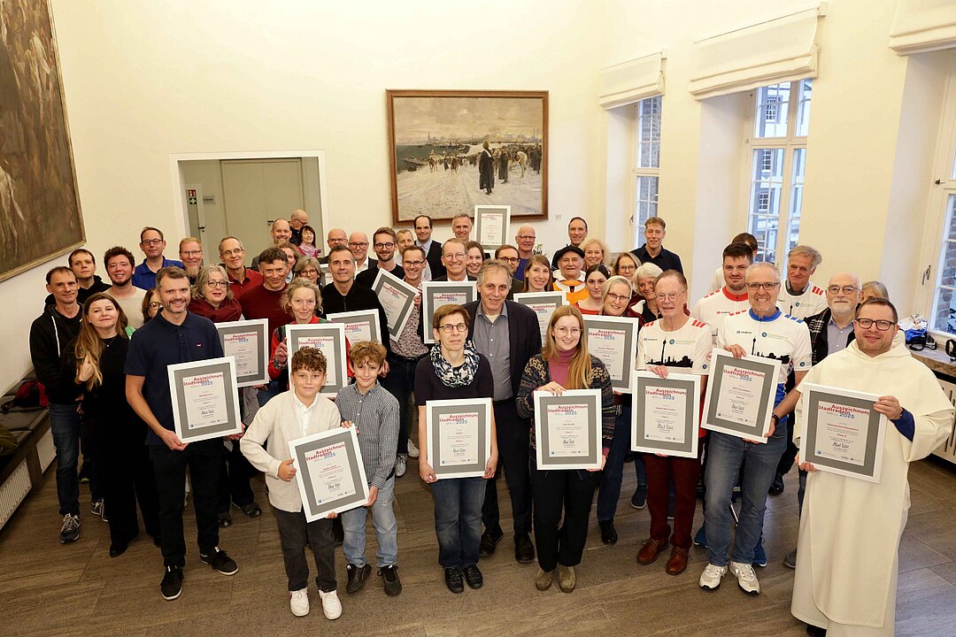 Mehrere Personen mit Urkunden in einem hellen Raum.